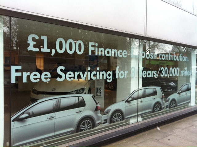 A photo of window vinyl advertising a new car