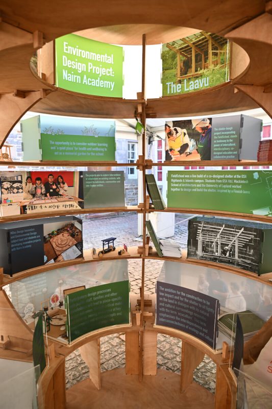 Interior view of illuminated Rural Lab exhibition structure highlighting educational graphics and wooden framework.
