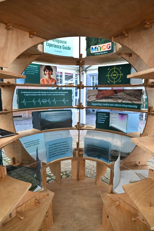 Circular wooden exhibition display at Glasgow School of Art’s Rural Lab showcasing illuminated educational panels.