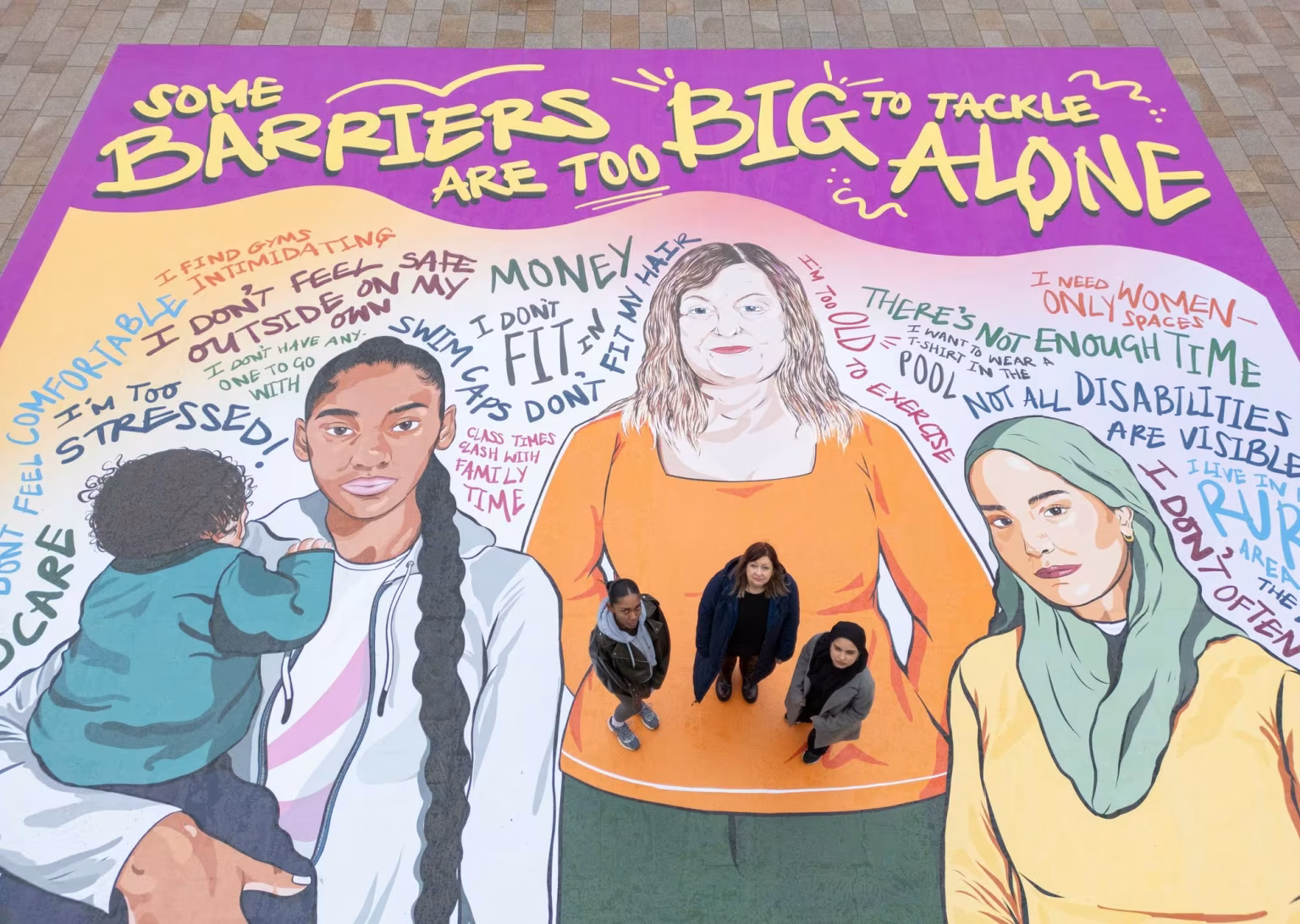 Mid-shot of campaign floor artwork with illustrated women and empowerment message in purple and orange design.