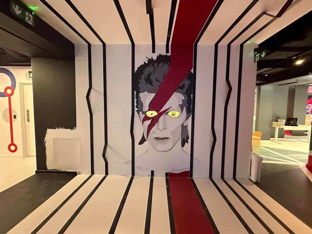 Perspective-distorting hallway at Paradox Museum featuring striped red, white, and beige wall graphics with character illustration.