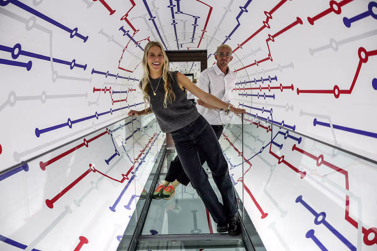 Person standing inside an optical-illusion tunnel at Paradox Museum surrounded by red and blue linear wall graphics.