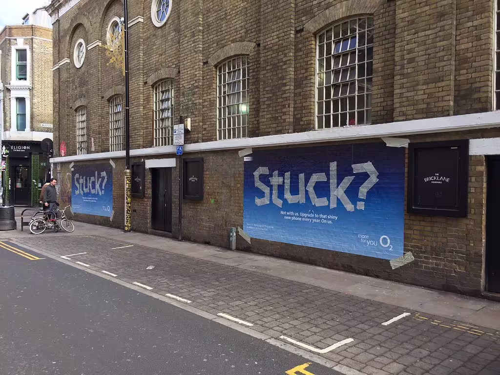 WW100 branded vinyl graphic applied across a brick wall exterior, wide view