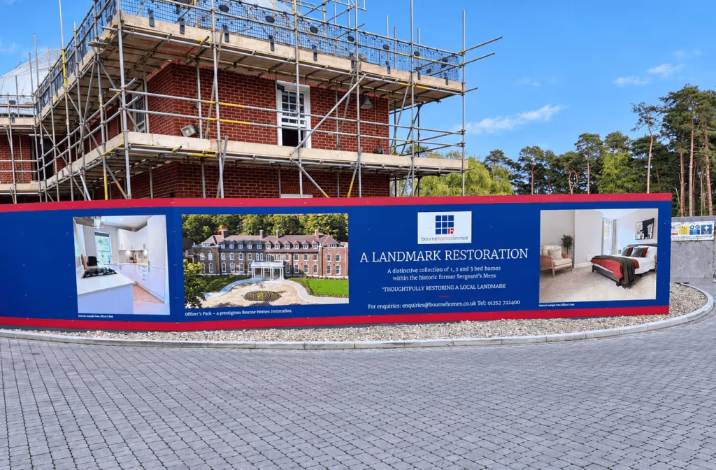 Wide view of printed ACM hoarding installed around the curved Sergeants Mess development site.